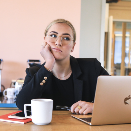 A blonde woman looking off into the distance while she's supposed to be working. If you struggle with procrastination, contact us today to begin our anxiety counseling in NYC, NY. We can help support you to break the procrastination cycle.