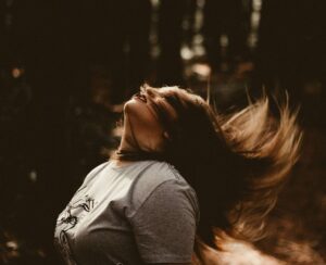 A young women throwing her hair in the air. Representing how anxiety therapy in NYC can help you feel free! Get started with anxiety counseling today. 