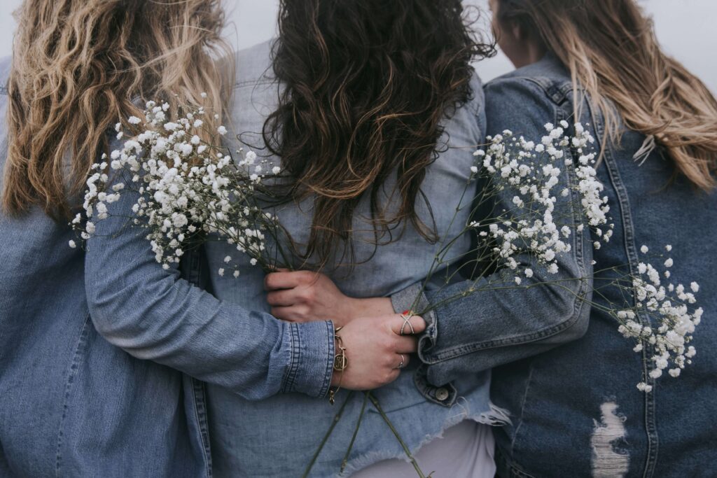 Three women holding baby's breath flowers while hugging. Discover the common causes of anxiety with the help of an anxiety therapist in NYC, NY. Call today to get started with anxiety therapy. 