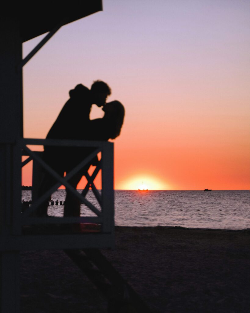 A couple kissing on a beach, in front of sunset. Work through your anxious attachment with an anxiety therapist in NYC, NY. Call today to begin anxiety counseling. 