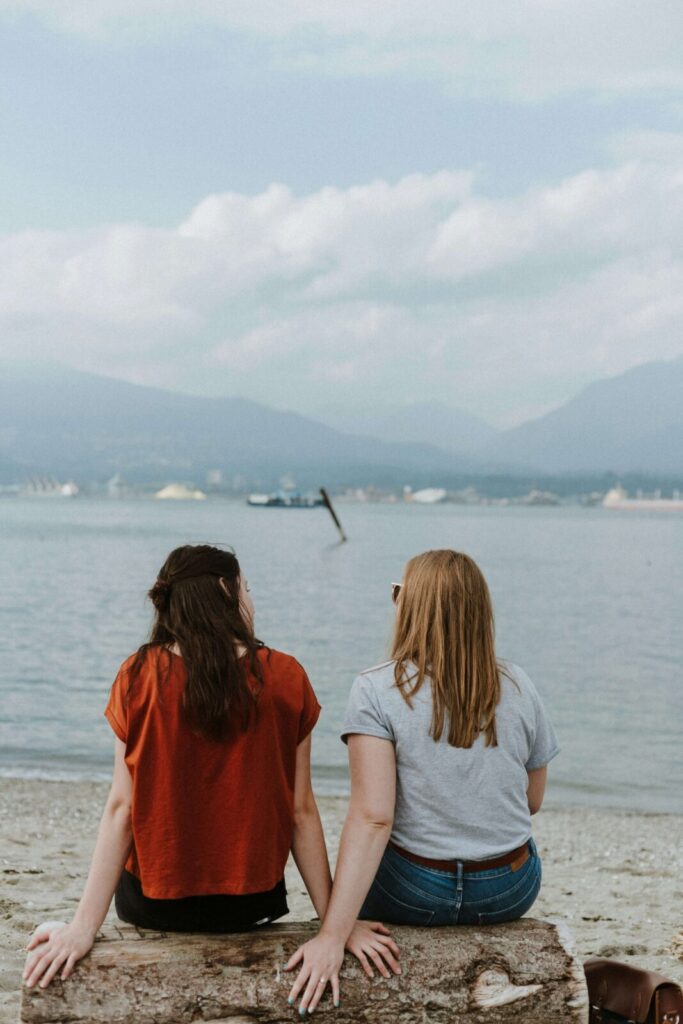 Two friends sitting together on a rock. With the help of an anxiety therapist in NYC, NY, you can heal your anxious attachment. Call today to begin anxiety therapy!