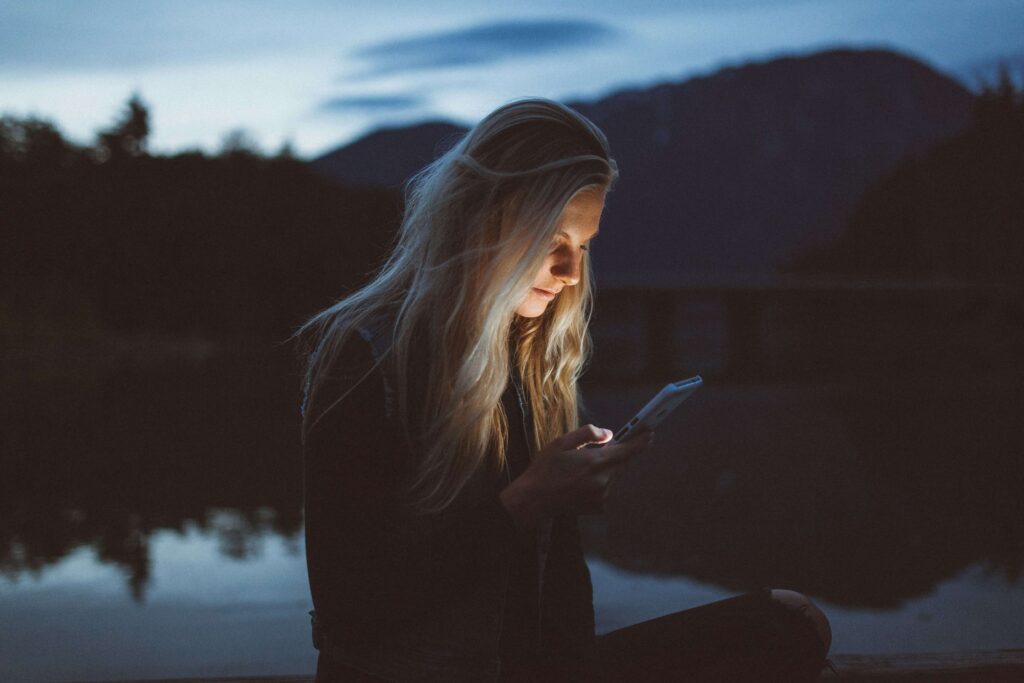 A young woman looking at her phone in the dark. By working with an anxiety therapist in NYC, you can find relief. Begin the work in NYC anxiety therapy today!
