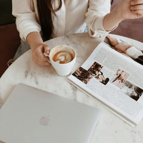 A woman drinking coffee and reading magazine. Anxiety symptoms can feel overwhelming. Learn coping strategies from a NYC anxiety therapist here!