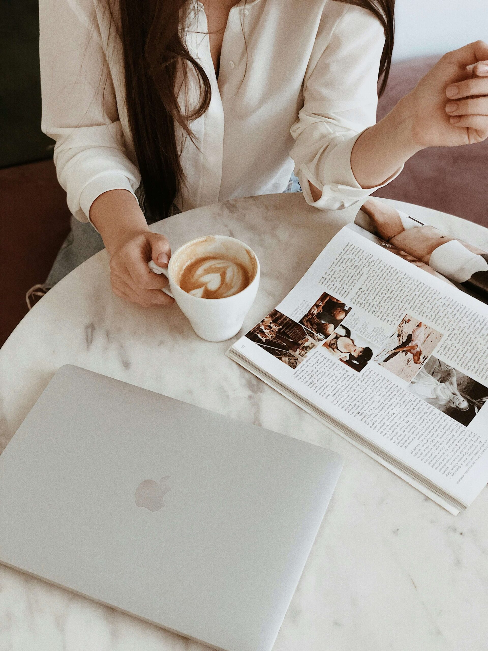 A woman drinking coffee and reading magazine. Anxiety symptoms can feel overwhelming. Learn coping strategies from a NYC anxiety therapist here!