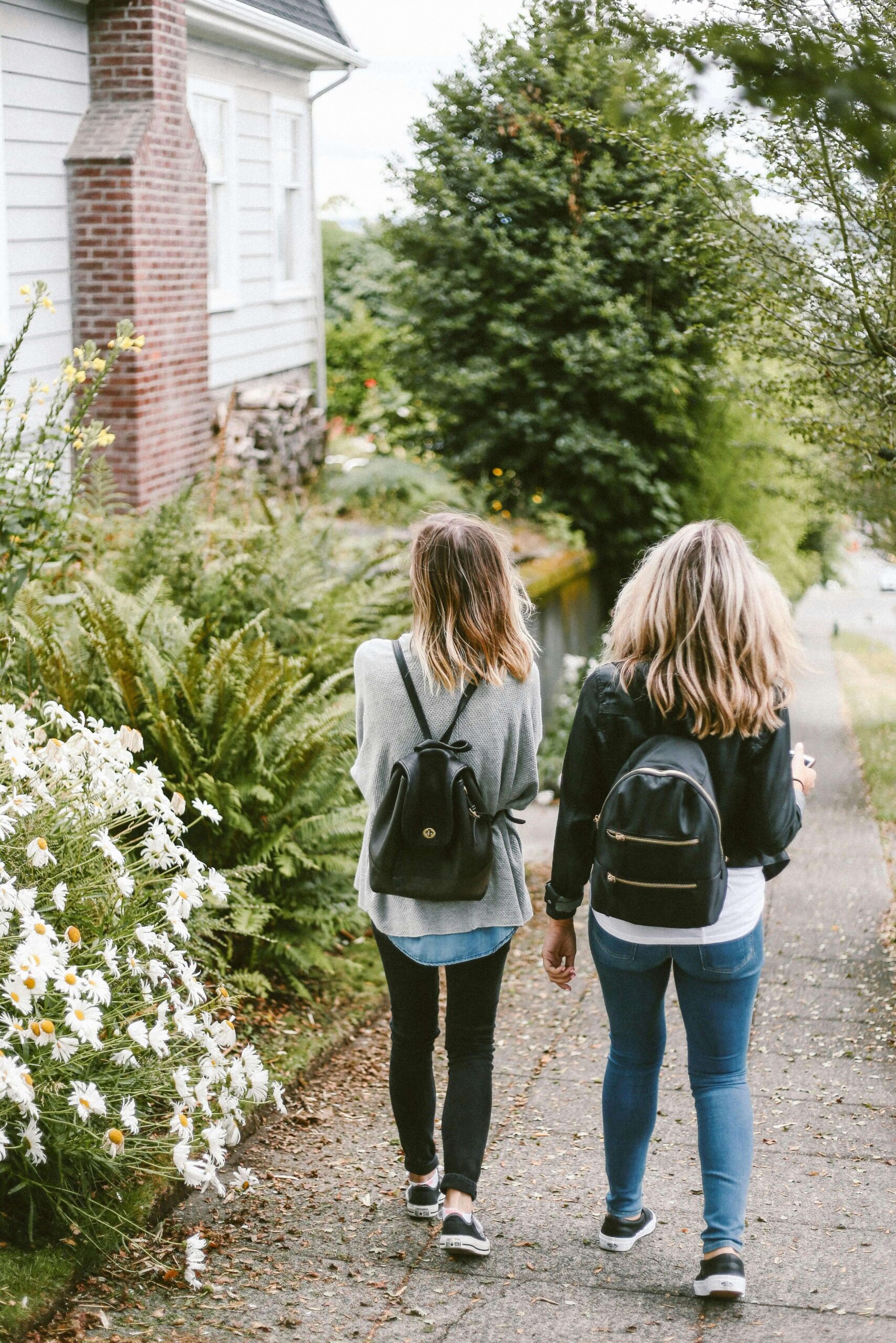 Two friends walking down a sidewalk together. Representing how calling a friend can help you alleviate anxiety. Learn more coping strategies for anxiety by starting anxiety counseling in NYC, NY.