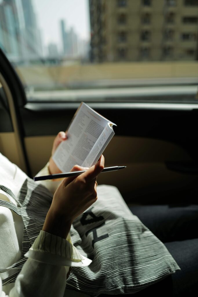 A woman reading a book in a taxi. Even during busy times, you can practice mindfulness! Discover more anxiety coping skills in anxiety therapy in NYC, NY. 
