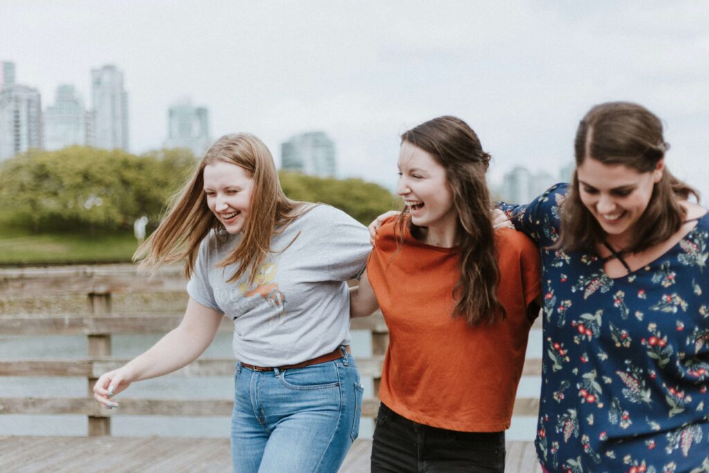 A group of three women laughing and walking together through the park. Want to learn more about self-compassion & anxiety? Begin anxiety counseling in NYC, NY today!