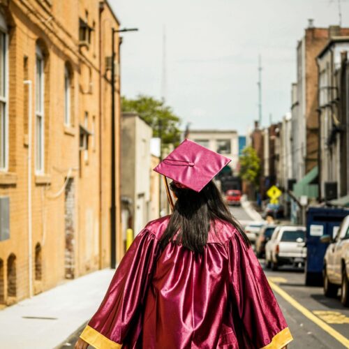 An individual with long brown hair wearing a graduation cap & gown. Representing how the college to career transition may seem daunting. Develop coping skills for anxious moments in NYC anxiety counseling.