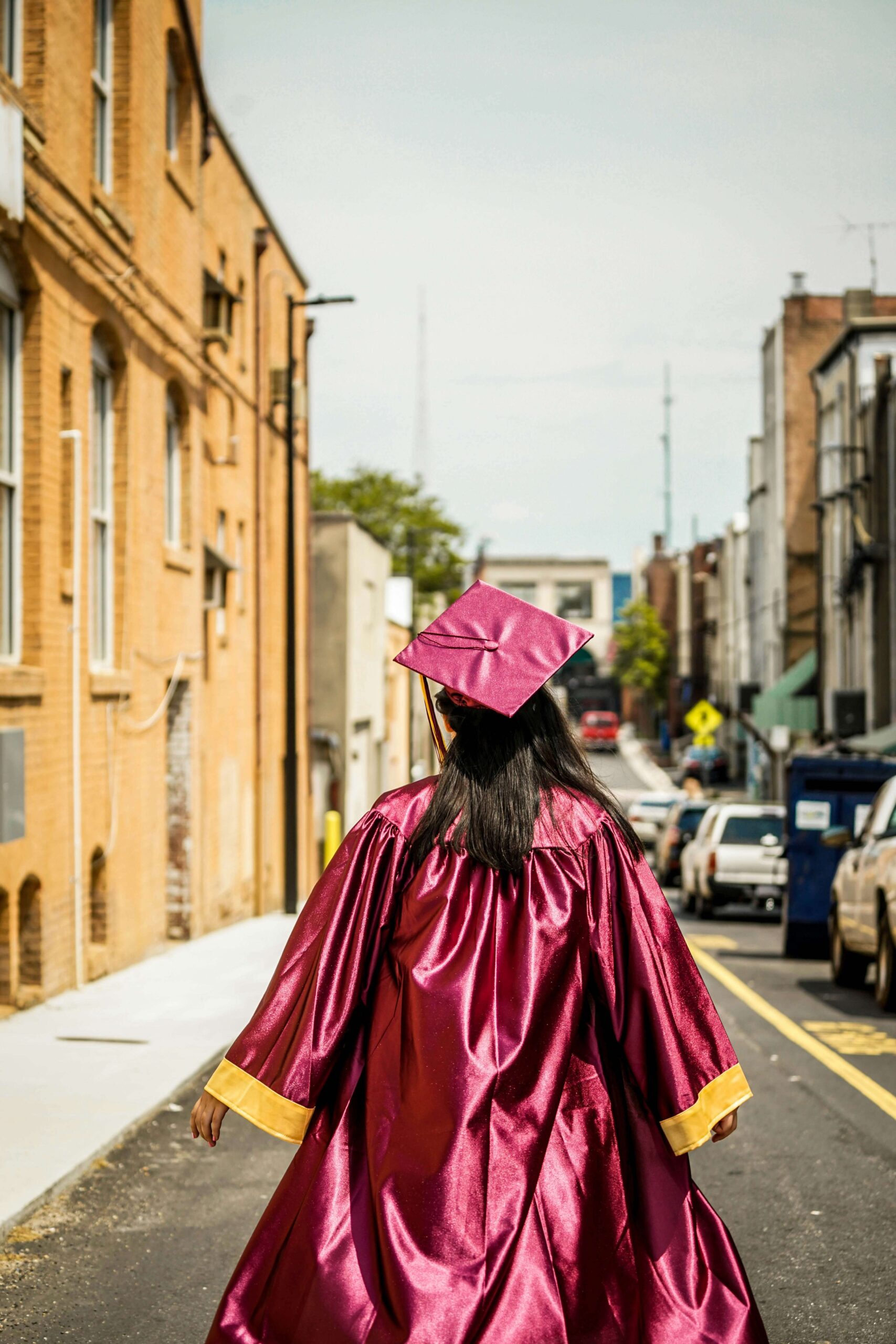 An individual with long brown hair wearing a graduation cap & gown. Representing how the college to career transition may seem daunting. Develop coping skills for anxious moments in NYC anxiety counseling.