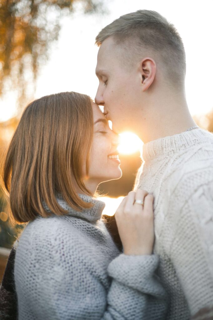 A man kissing a woman's forehead during a sunset. Anxiety counseling in NYC, NY can help your ROCD & anxious attachment. Start your recovery journey today!