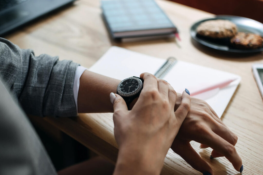 A business woman looking at the watch on her wrist. This represents how the common causes of procrastination such as fear of failure & low self-efficacy. To learn more about procrastination, call us today to begin anxiety counseling in NYC, NY.