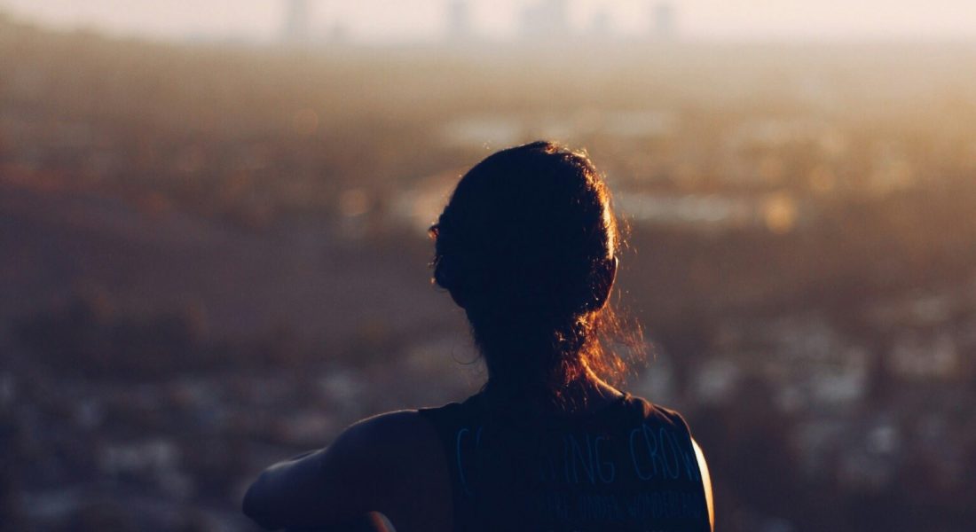 An individual sitting on an edge, looking at a skyline of a city. Gold Therapy NYC is here to help you! We offer anxiety counseling in NYC.