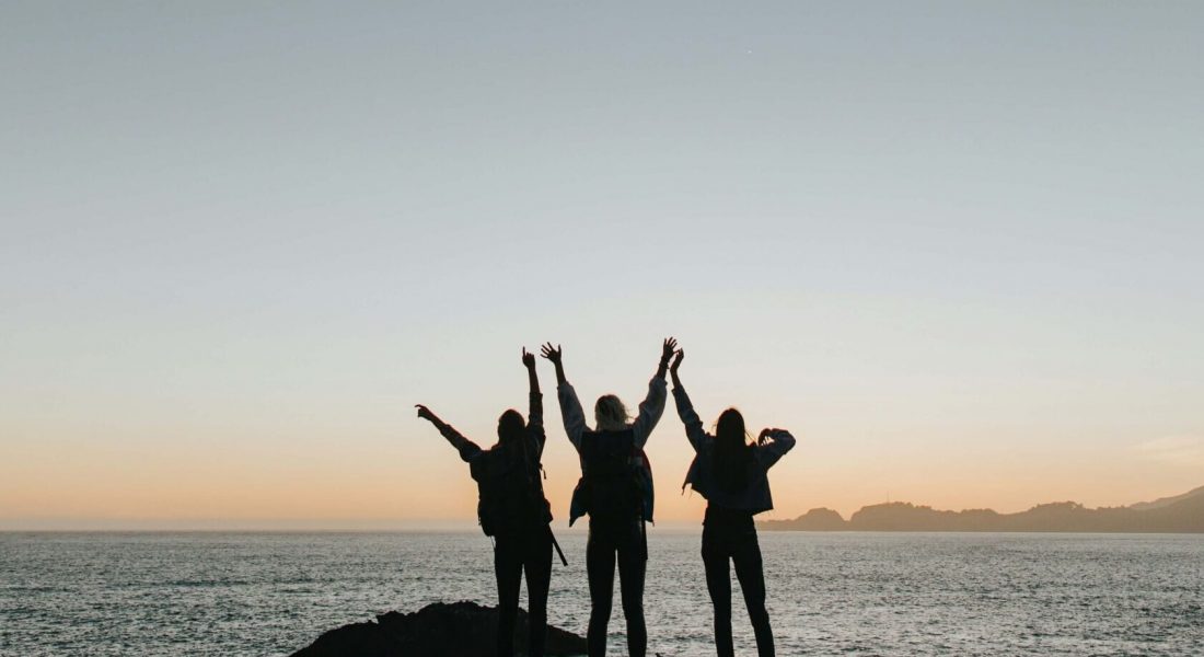 A group of friends holding hands while standing by water. Get the support you deserve in anxiety therapy in NYC, NY. Work with an anxiety therapist today to find anxiety coping strategies.