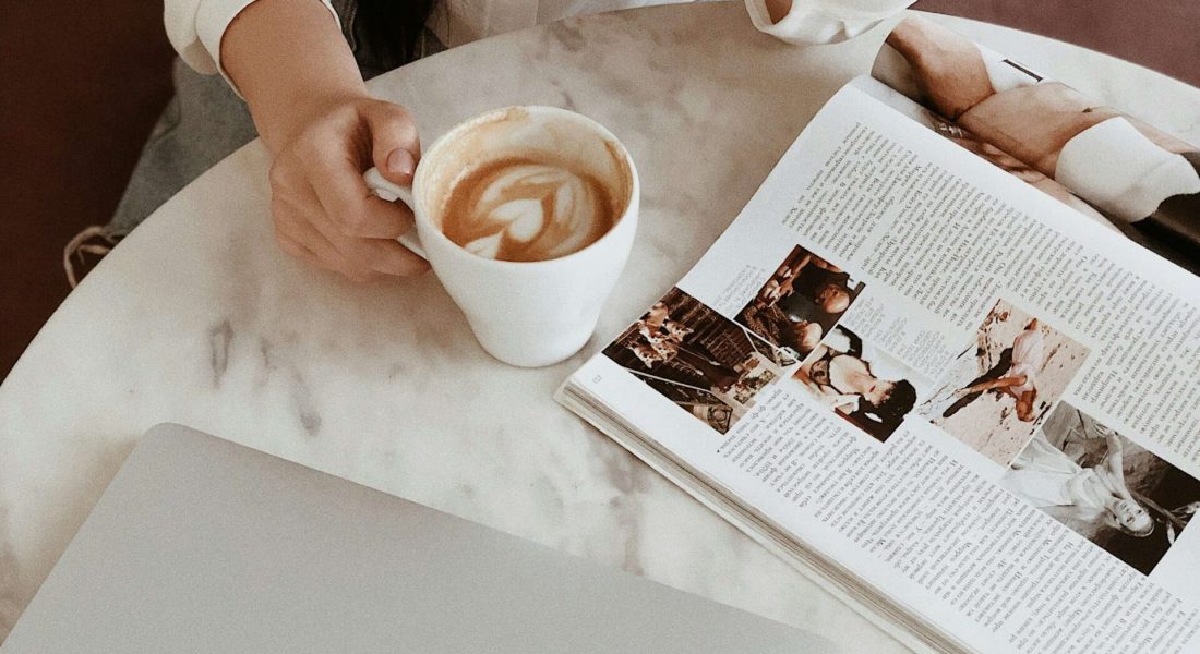 A woman drinking coffee and reading magazine. Anxiety symptoms can feel overwhelming. Learn coping strategies from a NYC anxiety therapist here!