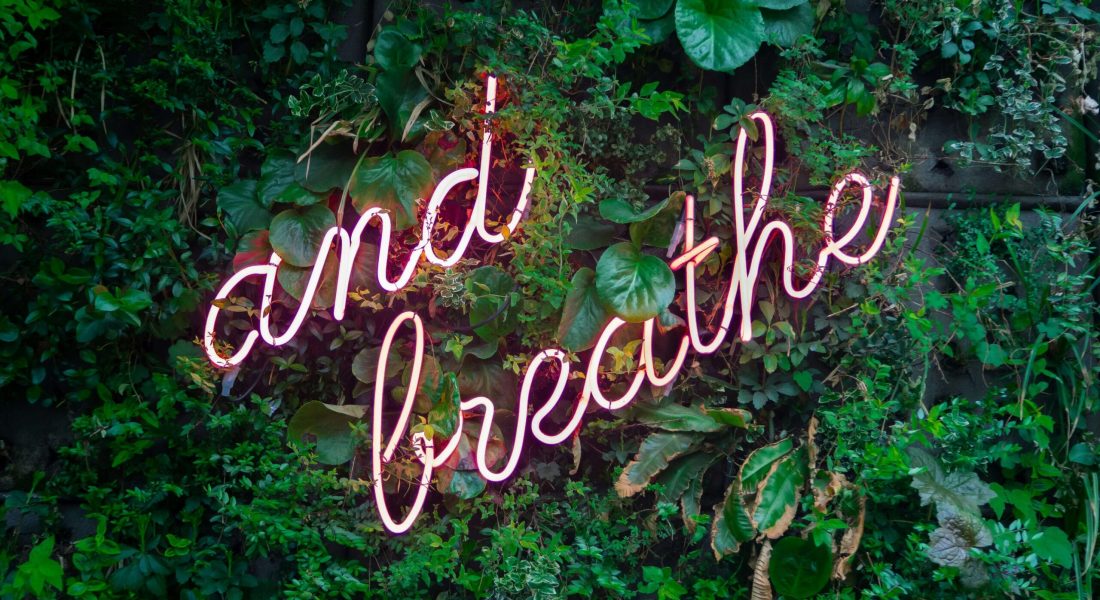 A neon sign that reads "and breathe". Representing how mindfulness can help your anxiety. Begin anxiety counseling in NYC today!